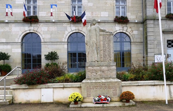 monument au mort devant bâtiment de la mairie avec une gerbe et des fleurs